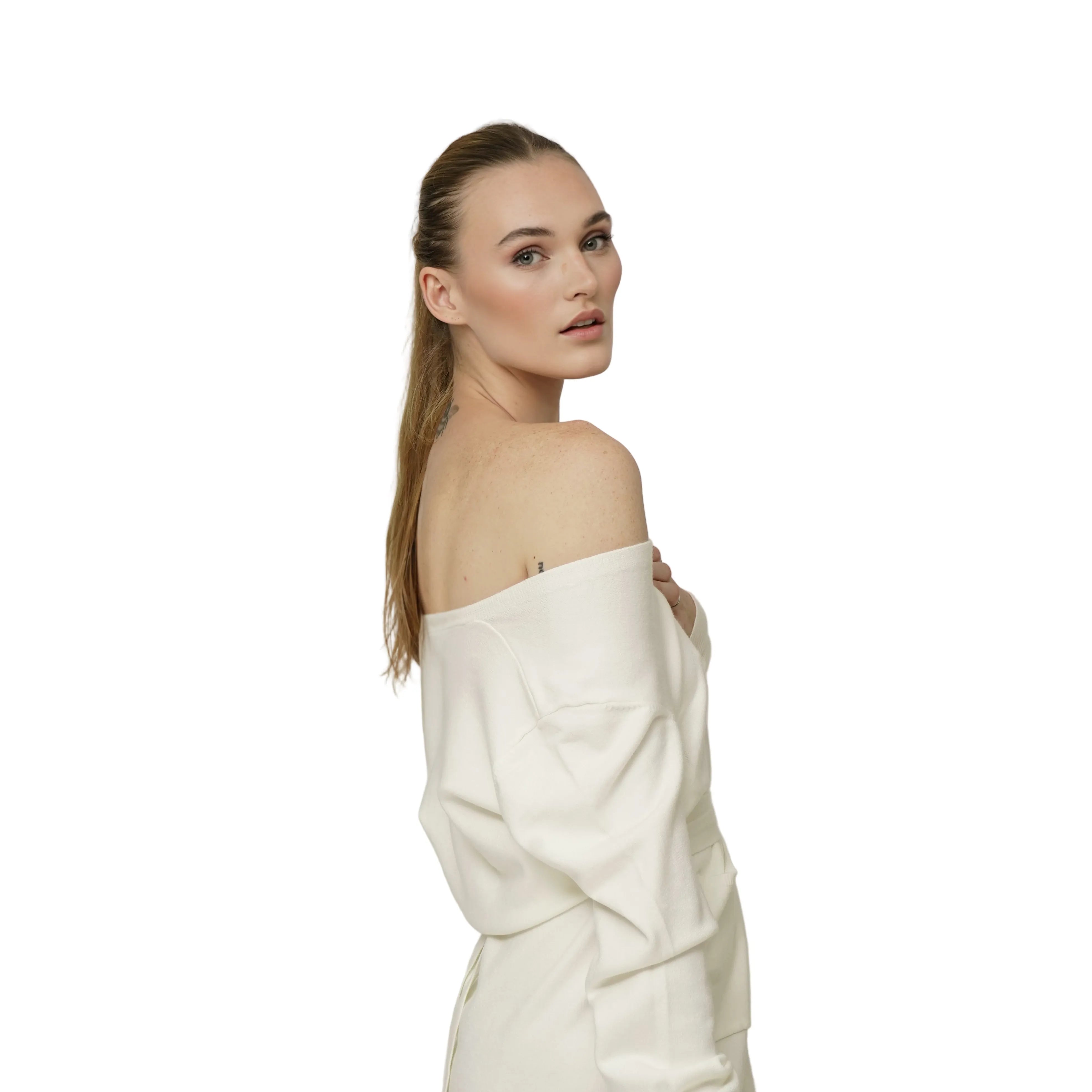 Woman wearing an ivory off-shoulder dress against a plain background
