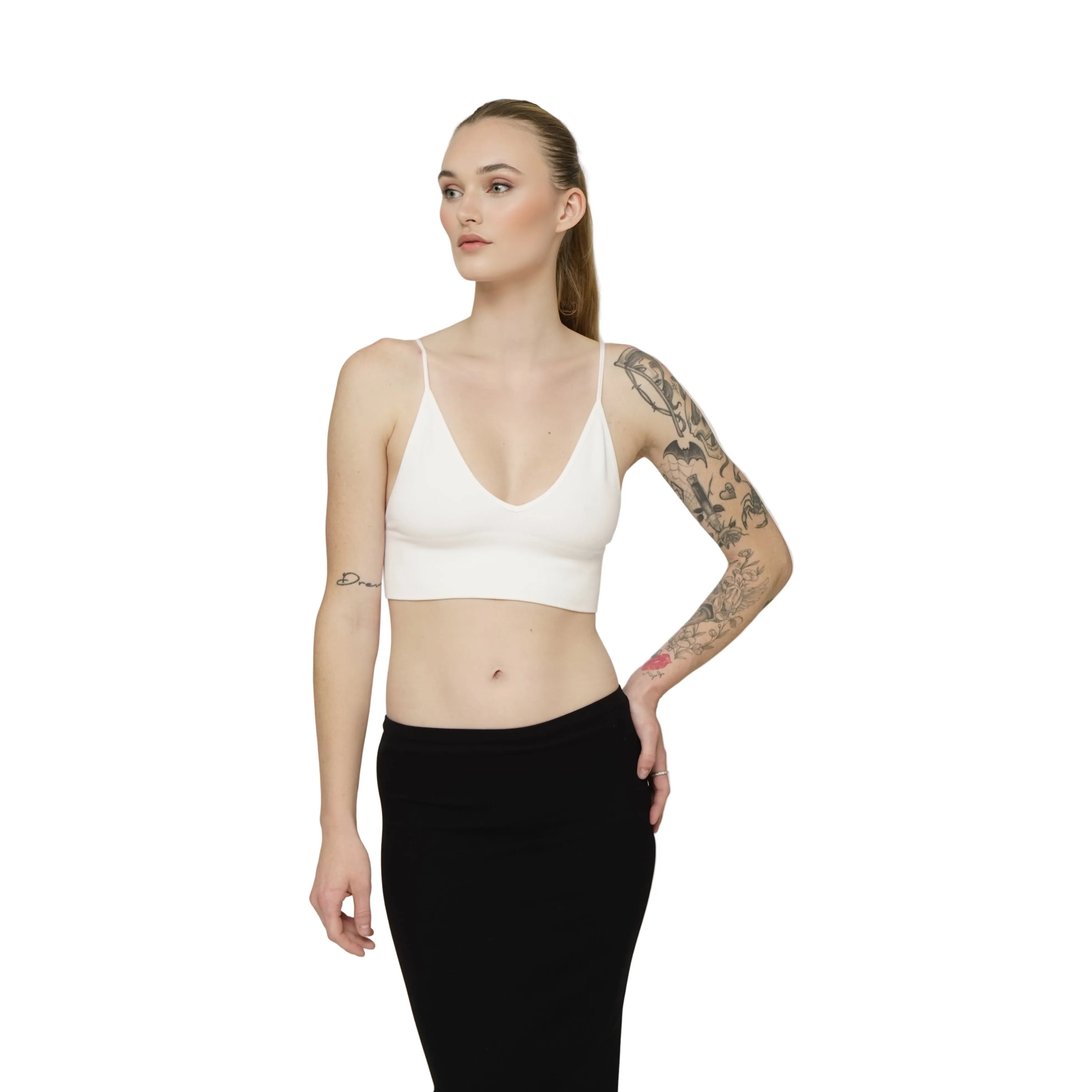 Woman wearing a white bralette and black skirt on a plain background