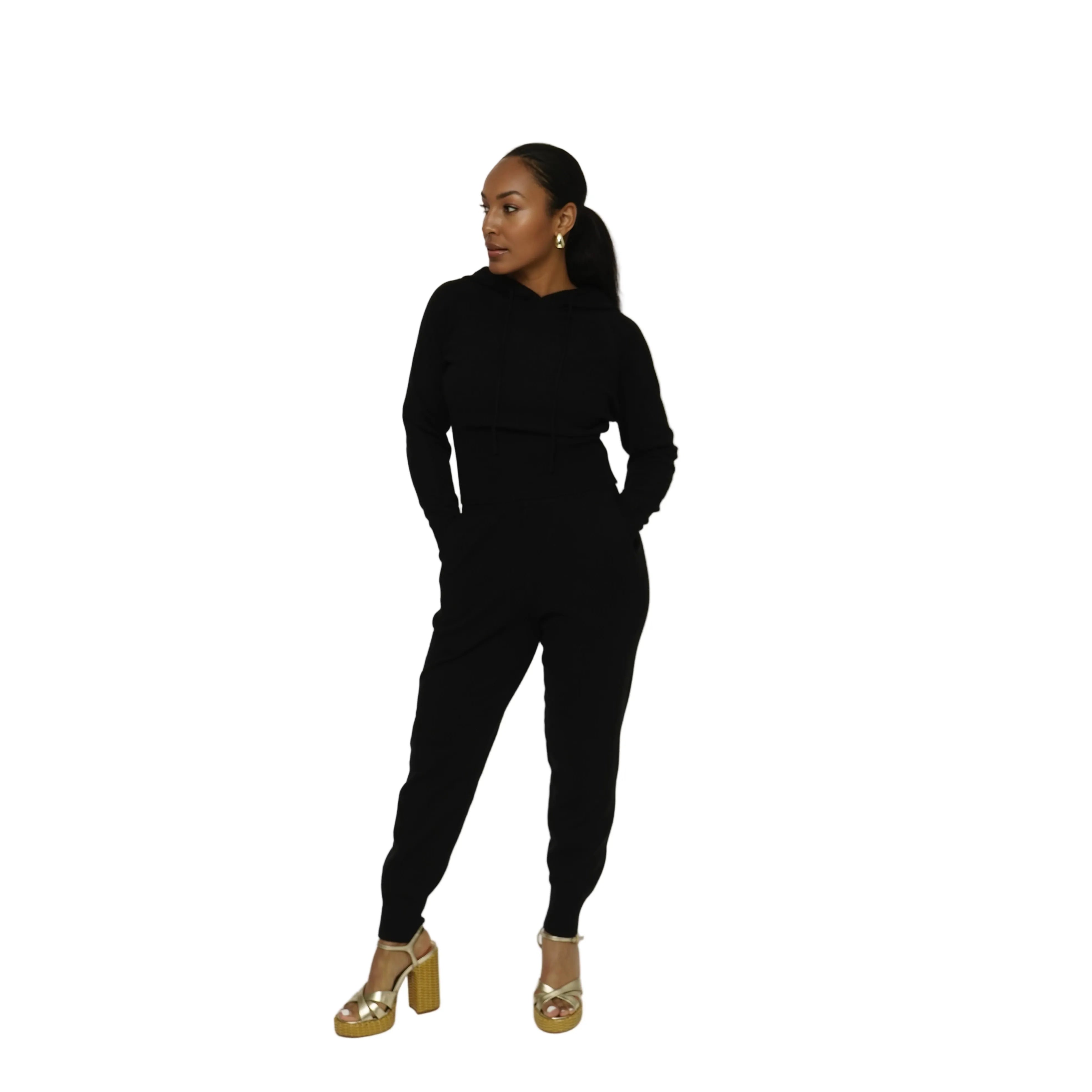 Person wearing a black outfit with gold sandals on a white background