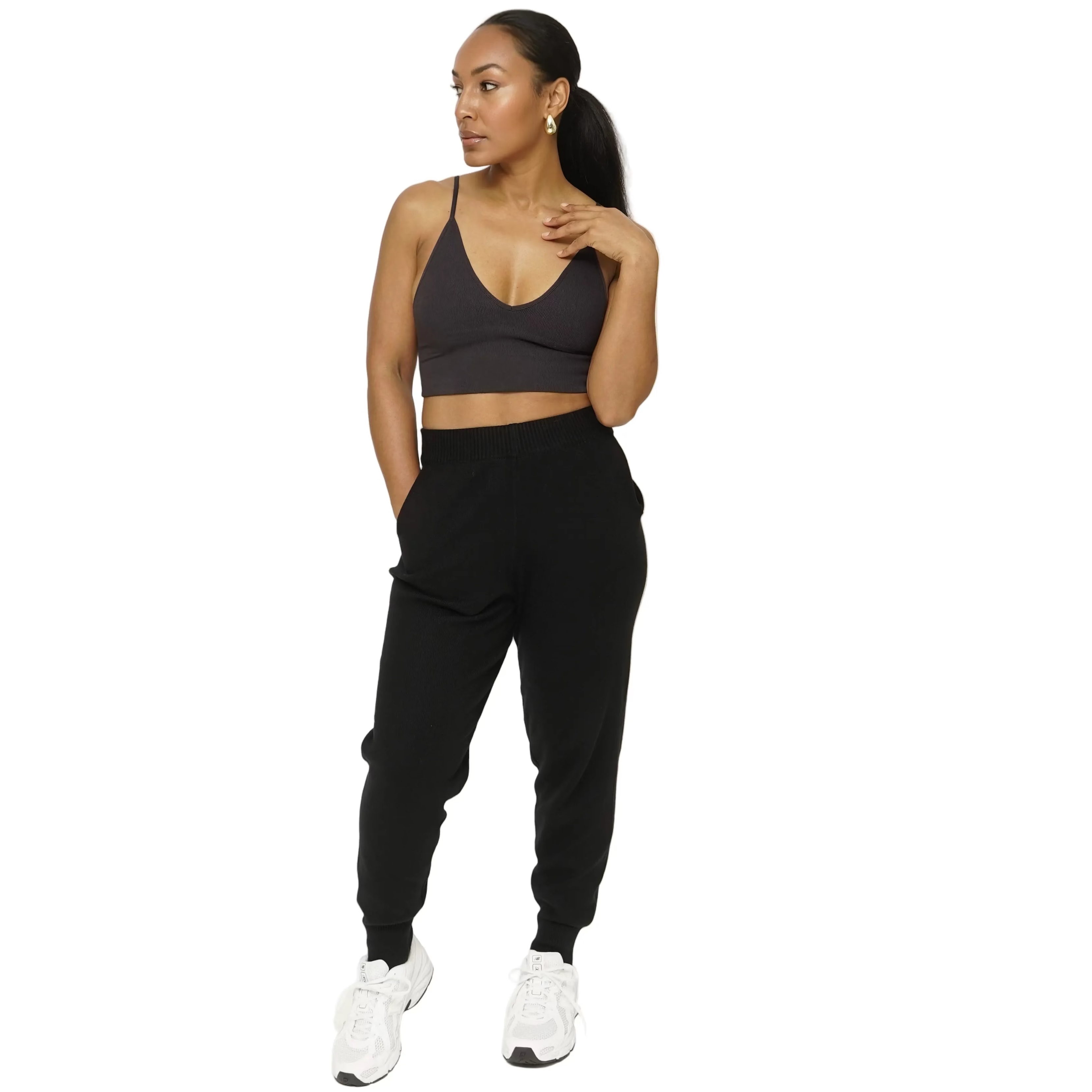 Woman wearing a black sports bra and jogger pants on a white background